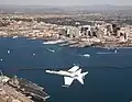 F/A-18 Hornet volant au-dessus de San Diego. L'USS&nbsp;John C. Stennis est visible.