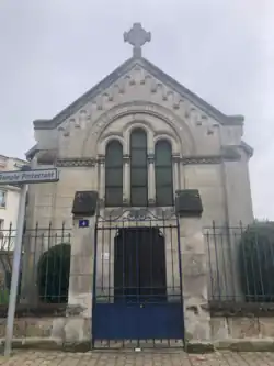 Photo en couleur de la façade, derrière une grille fermée.