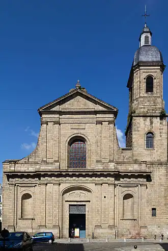 La photographie est prise de l'extrémité est de la rue du Guesclin, afin de souligner la mise en perspective de la façade. On voit le sommet du beffroi, mais les côtés de la façade et la tour (au nord) sont masqués par les immeubles de la rue. L'inscription christo salvatori en médaillon au-dessus du portail indique la dédication de l'église au Saint-Sauveur.