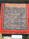 Porte-bébé Miao. Broderie et tissage façonné tujia sur galons encadrant un carré d'impressions à la cire (batik Miao). Yunnan Nationalities Museum, Kunming.
