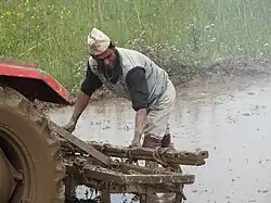 Homme travaillant sous la pluie derrière un tracteur