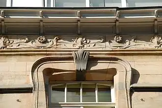 Couronnement d'une fenêtre du deuxième étage et détail de la frise : palmettes, marguerites et feuillages ondulants