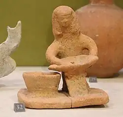 Femme assise tenant un plat ovale, VIIIe&nbsp;– VIe&nbsp;siècle av. J.-C. Actuelle Akzib. Musée du Louvre.