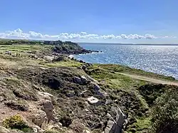 Un chemin côtier surplombe la mer en conduisant à un fort.