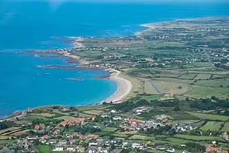 Vue aérienne d'un paysage plat, à gauche la mer qui pénètre sur les terres à droite en plusieurs petites anses séparées par de petites pointes rocheuses.