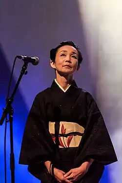 Photo de Maliko Oka au micro sur scène en 2016.