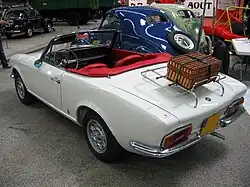 Vue arrière d'une Fiat 124 Sport Spider avec une véronique sur le coffre.