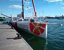 Vu de trois quarts avant, voilier blanc et violet amarré au ponton.