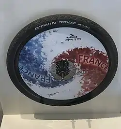 La flasque de Kathy Laurent aux Jeux paralympiques d'été de 2012, montée sur une roue de vélo et signée par toute l'équipe féminine de handibasket