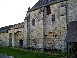 Façade ouest de la ferme de Fourcheret, avec l'ancienne porterie (à gauche) et un pan de mur d'origine du logis, avec trois contreforts. Plus à droite, les contreforts ont disparu.