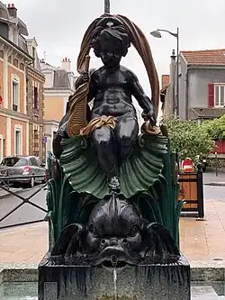 Fontaine. Chérubin de bronze assis dans une coquille saint Jacques, surmonte un poisson. Voûte de drap noué par une rosette sur la cuisse et la coquille.