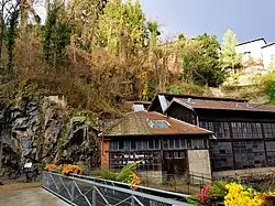 Photographie de l'entrée principale de l'usine avec la falaise rocheuse au-dessus.