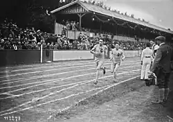Photographie en noir et blanc de deux coureurs à pied lors d'une course dans un stade.