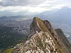 Arêtes rocheuses dominant une agglomération en arrière-plan.