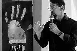 un homme avec lunettes et bouc avec un micro