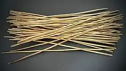 Photographie d'un entassement de fins bâtonnets blancs sur fond gris.