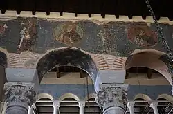 Chapiteaux, mosaïques, et fresques du XIIIe&nbsp;siècle sur le mur.