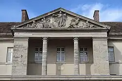 Photographie en couleur du fronton d'un bâtiment, soutenu par des colonnes.