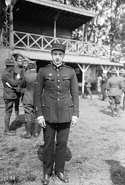 Photographie en noir et blanc d'un homme debout en tenue militaire à l’extérieur d'un bâtiment