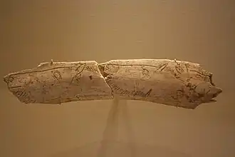 Os gravé, deux têtes de cheval tournées à gauche et une petite tête de cervidé tournée à droite.