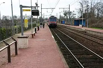 Voies et quais avec le départ d'un train Transilien en direction de Malesherbes.