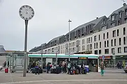 Bus à l'arrêt avec voyageurs et bagages en premier plan.