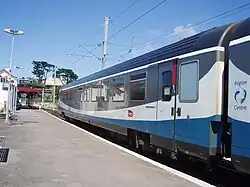 Vue d'un wagon bleu et blanc sur un quai de gare.