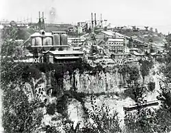 Photo en noir et blanc prise depuis le versant côté Haute-Savoie et montrant les aménagements techniques sur le plateau de l'Ain
