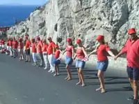 Des hommes et des femmes avec des polos et des casquettes rouges, et des jupes ou pantalons bleus ou blancs se donnent la main