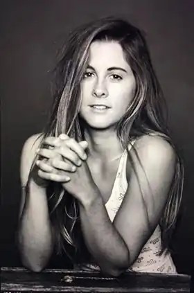 Photographie en noir et blanc d'une jeune femme assise à une table