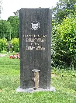 Une tombe noire, avec un visage de chat en blanc au-dessus du nom des défunts.