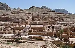 vue éloignées extérieures de ruines avec des escalier, des colonnades. Quelques personnes marchent dans le temple.