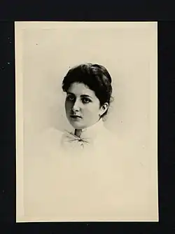 Jeune fille aux cheveux noirs coiffée d'un chignon le regard au loin.