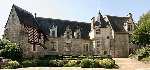 Photographie d'un manoir : des colombages à gauche ; une petite tour à gauche.