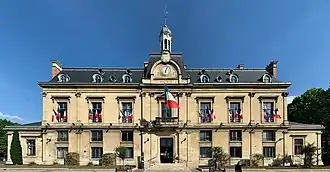 façade d'un grand bâtiment ocre décore de drapeaux tricolore portant l'inscription « Mairie » au premier étage