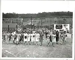 Changement d'équipe au Y-12 National Security Complex à Oak Ridge pendant le projet Manhattan. Sur le panneau d’affichage : « make CEW Count -- Continue to protect project information » (continuez à protéger les informations du projet.).