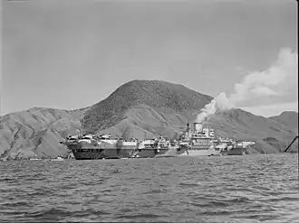 Photographie noir et blanc ancienne d'un porte-avions dans une ria.