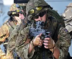 photographie en couleur montrant un groupe de soldats avançant en file indienne sur un navire