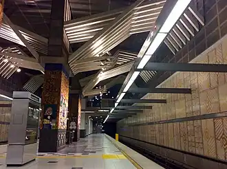 Vue en contre-plongée du quai. On voit des sortes de mosaïques sur le mur.