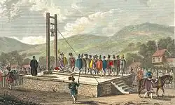 Une gravure historique représentant une exécution publique sur une plateforme surélevée. Au centre, une guillotine domine la scène. Une foule dense, vêtue d'habits d'époque, entoure un ecclésiastique prêchant. Le paysage rural en arrière-plan et les détails précis créent une atmosphère solennelle et documentaire.
