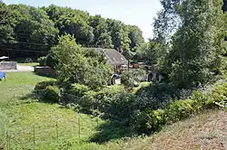 Une vieille maison entourée de végétation au milieu d'une petite vallée.