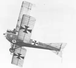 Photo noir et blanc d'un avion biplan en vol, vu d'en dessous.