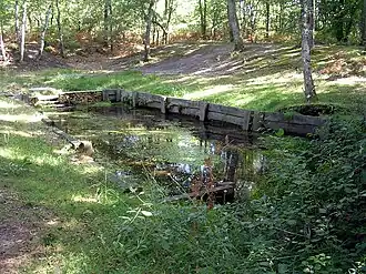 Bassin délimité par des pierres et des planches de la fontaine de Bayonne à Haut-Mauco.