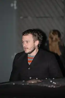 Un homme d’une trentaine d’années avec une barbe courte et une boucle d’oreille.