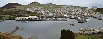 Heimaey vu vers le sud depuis Heimaklettur avec les volcans Eldfell et Helgafell à gauche et le port au premier plan.