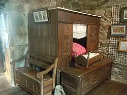 Lit-clos, banc-coffre, banc et berceau en exposition.