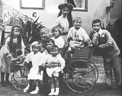 Photographie en noir et blanc montrant un groupe d'enfants dans et autour d'une charrette.