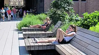 People sitting down on wooden chairs and reading books