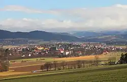 Photographie couleur d'un village dominé par un clocher, au cœur d'une large vallée.
