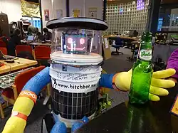 Photo d'un robot humanoïde tendant une main vers une bouteille de bière vide.